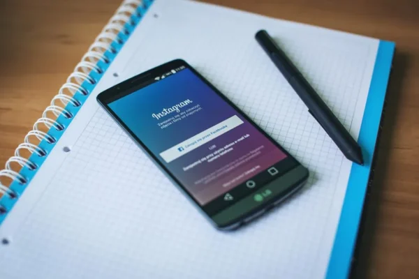 A smartphone displaying Instagram on a notepad with a pen, symbolizing social media and productivity.
