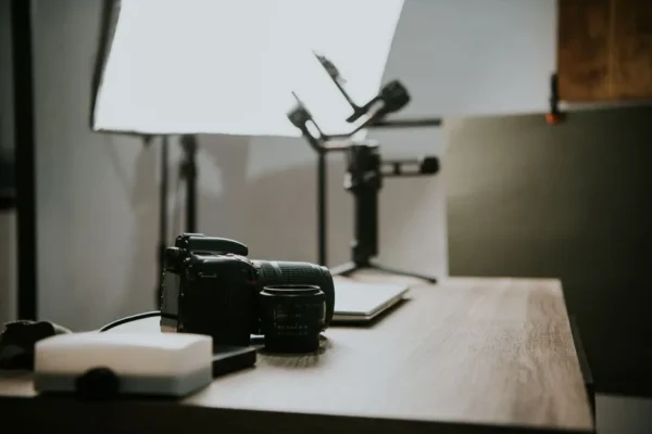 Close-up of a DSLR camera and lens on a wooden table in a studio setting, perfect for photography-themed content.