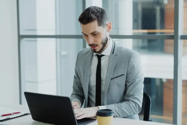 Businessman working on a laptop in a modern office setting.