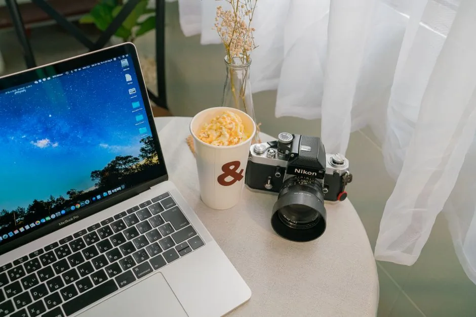 Cozy indoor workspace featuring a laptop, vintage camera, and coffee cup.
